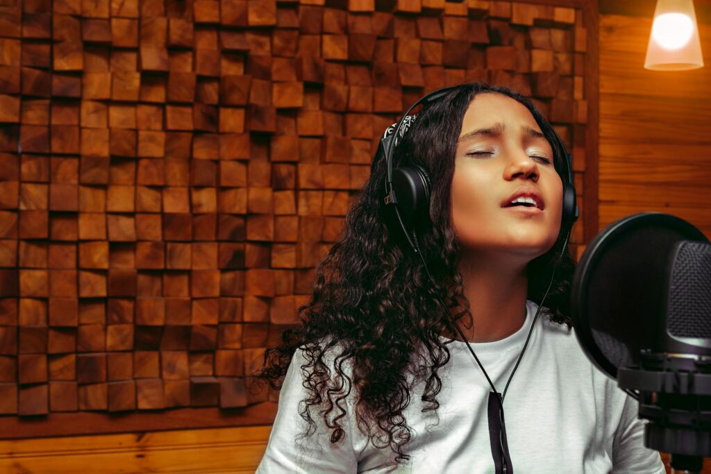 Fani Suárez Alicante A young woman passionately singing into a microphone in a professional recording studio.