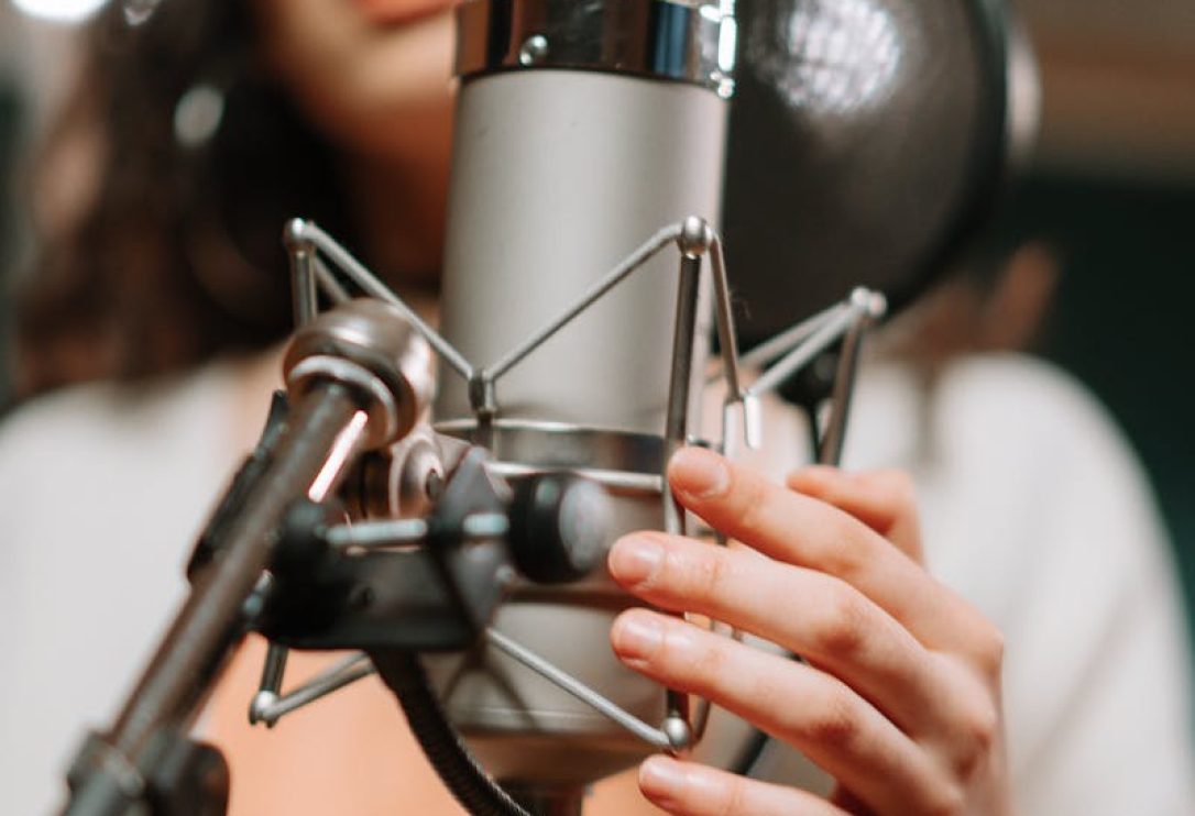 Fani Suárez Alicante A woman singing passionately into a condenser microphone in a modern music studio.